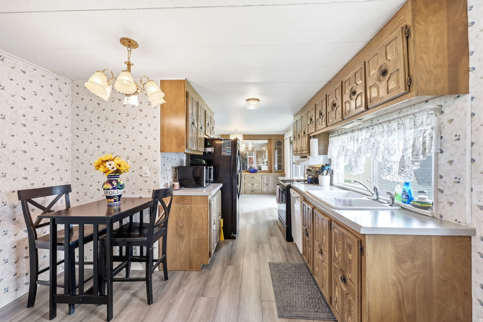 Kitchen featuring wood-finish flooring, extensive cabinetry, a double basin sink, and ample countertop space