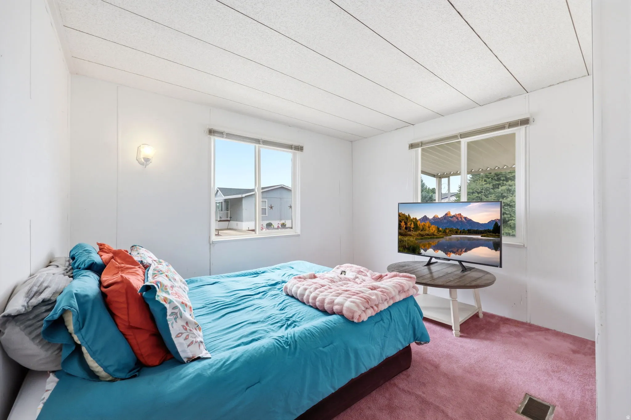 Bedroom featuring two large windows, white walls, and a textured ceiling