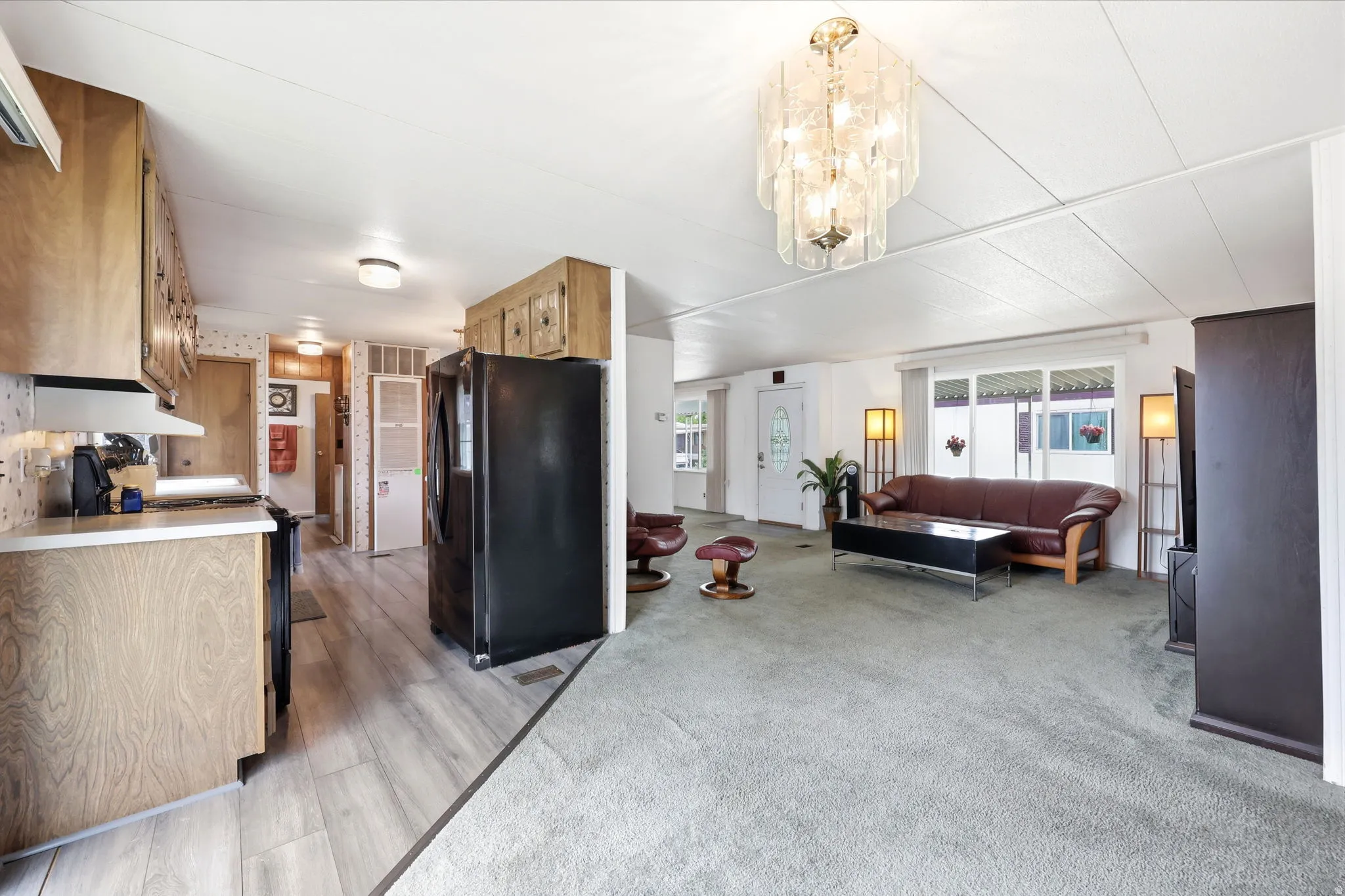 Open-concept living space featuring light wood-finish cabinetry, light wood-finish flooring, and a contemporary chandelier