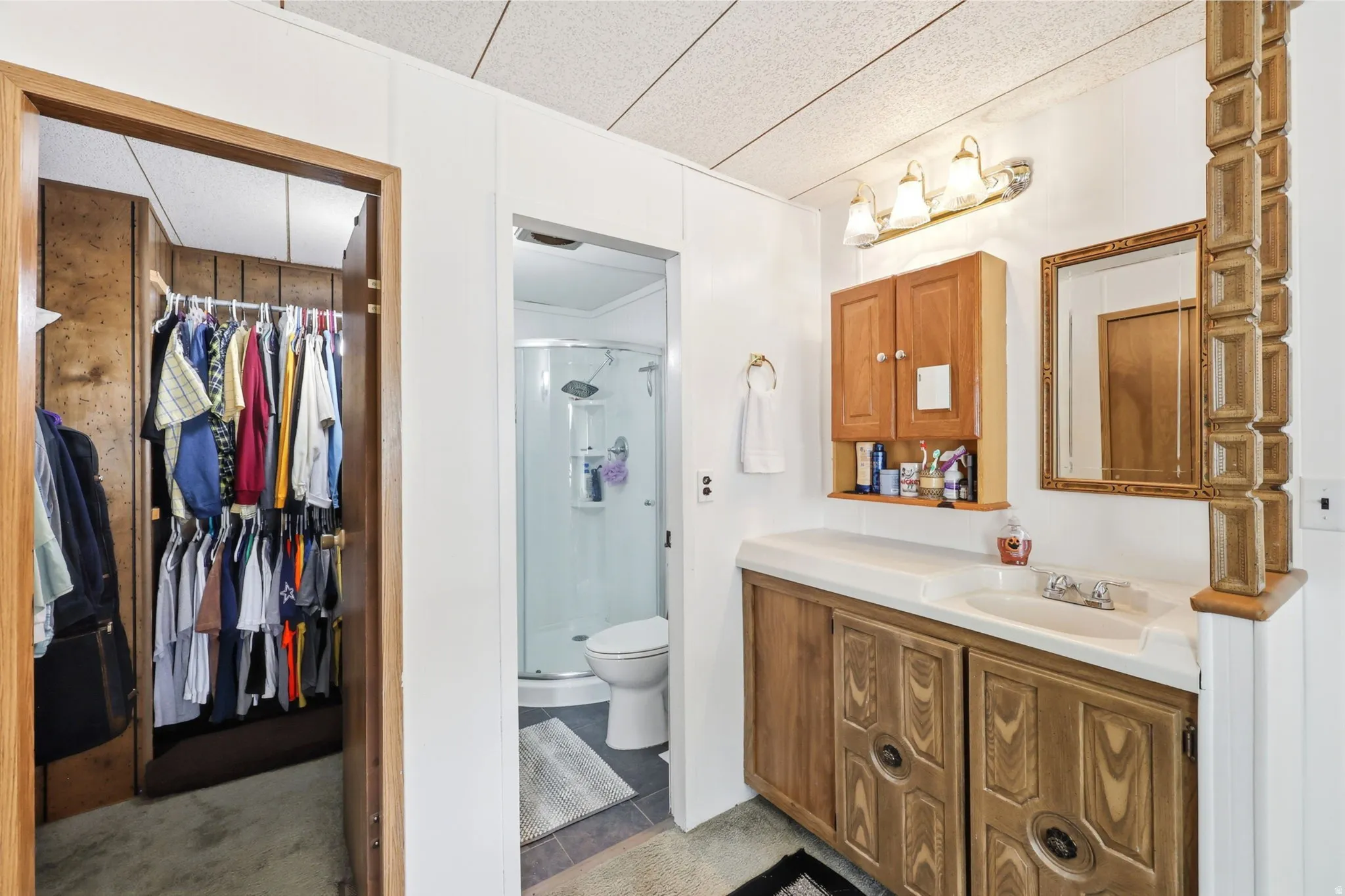 Bathroom featuring a wood-finish vanity with an integrated sink, a matching medicine cabinet, and a framed mirror