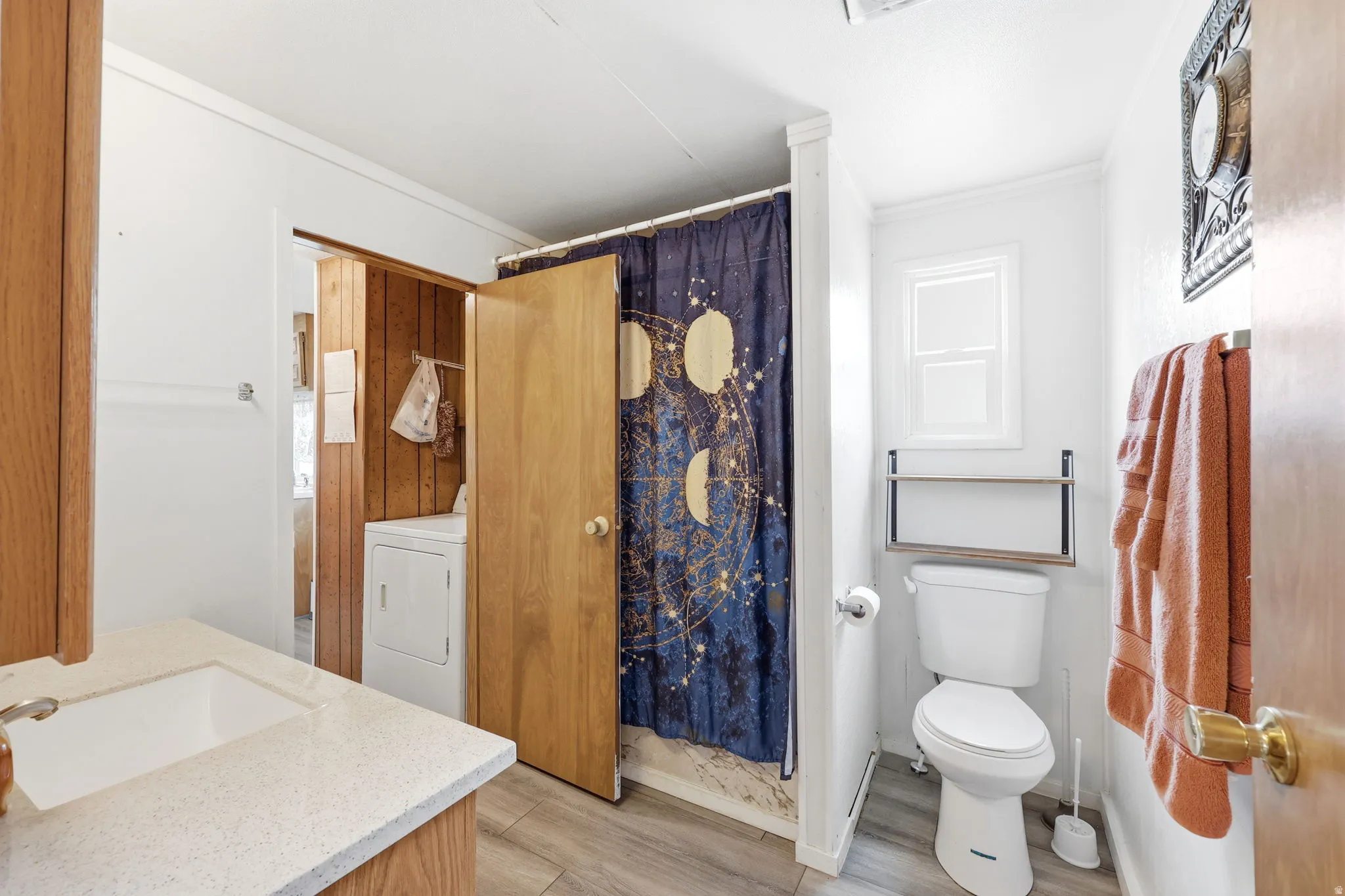Bathroom featuring a vanity with an integrated sink, wood-finish flooring, a toilet, and a window