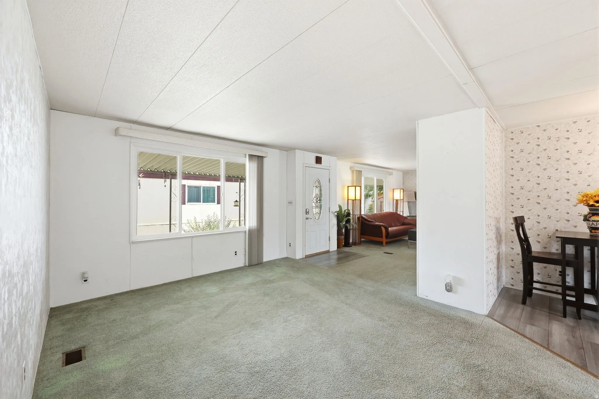 Spacious living area featuring light green carpeting and ample natural light from a large window