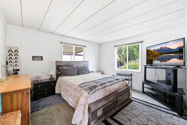 Spacious room featuring two windows, wood-finish flooring, white walls, and a textured ceiling