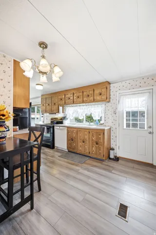Kitchen featuring wood-finish flooring, wood cabinetry, white countertops, and a full-light entry door