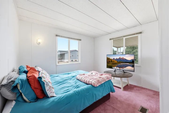 Bedroom featuring two large windows, white walls, and a textured ceiling