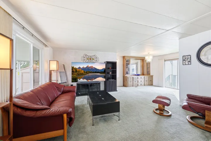 Spacious living area featuring light green carpeting and white walls