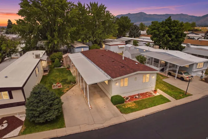 Property with light-colored siding and a red roof, featuring a covered carport and a manicured front lawn