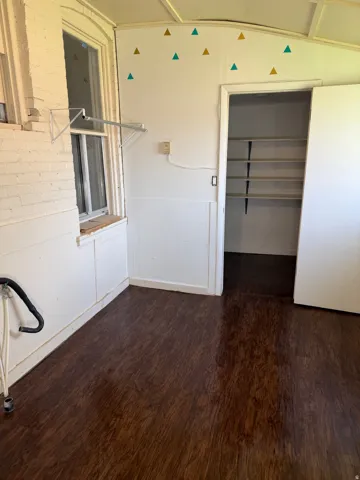Room with wood-finish flooring, white paneled lower walls, and a window