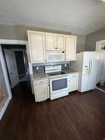 Kitchen featuring wood-finish flooring, white cabinetry, a built-in microwave, an electric range, and a side-by-side refrigerator