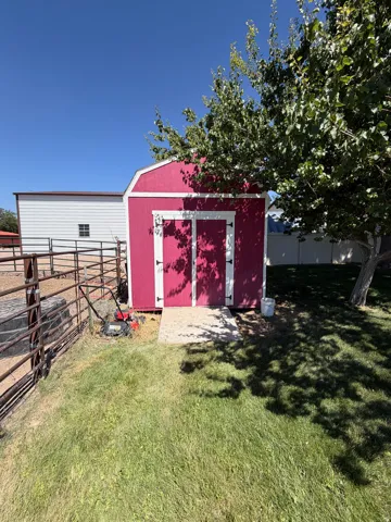Red-painted storage shed with white trim and a gambrel roof