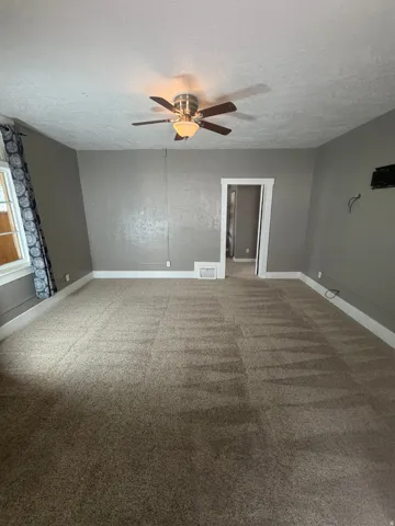 Spacious room with neutral-toned carpet flooring, light gray wall paint, and white trim molding