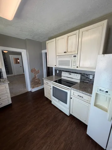 Kitchen featuring wood-finish flooring, light-toned cabinetry, granite countertops, and a mosaic tile backsplash
