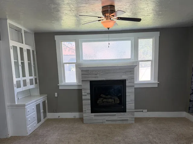 Living area featuring a textured gray fireplace surround, integrated electric fireplace, and a white built-in hutch with glass-front cabinetry