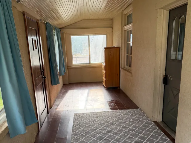 Enclosed porch featuring wood-finish flooring, white paneled ceiling, multiple windows, and a flush-mount ceiling light fixture