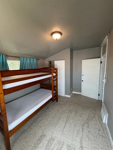 Carpeted room featuring a window with turquoise drapes, a ceiling-mounted light fixture, a paneled door, and a sliding closet door