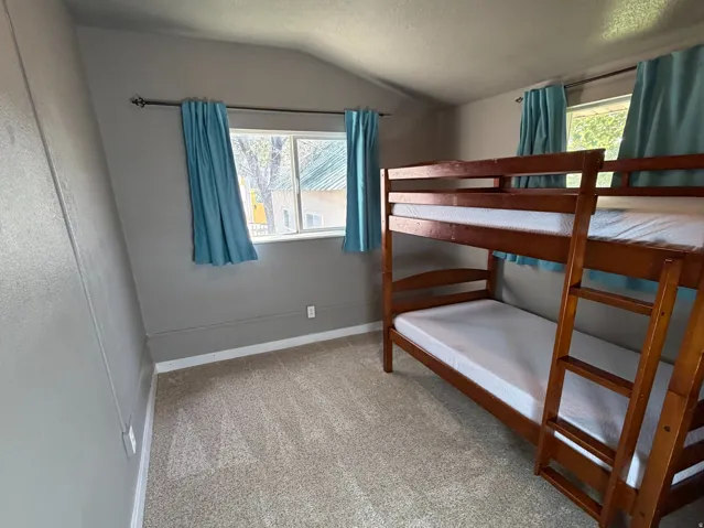 Carpeted room featuring two windows, an angled ceiling, and a ceiling-mounted light fixture