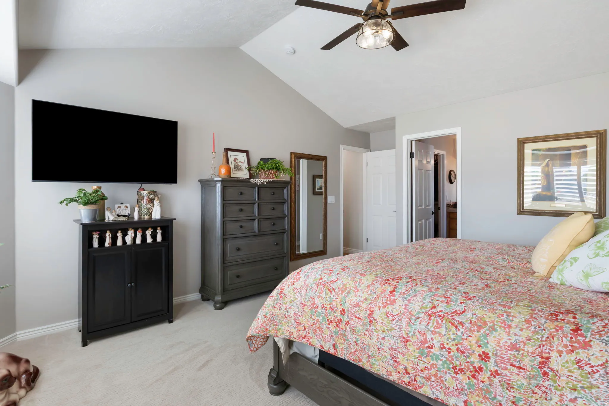 Carpeted room featuring a ceiling fan, vaulted ceiling, and light gray wall paint