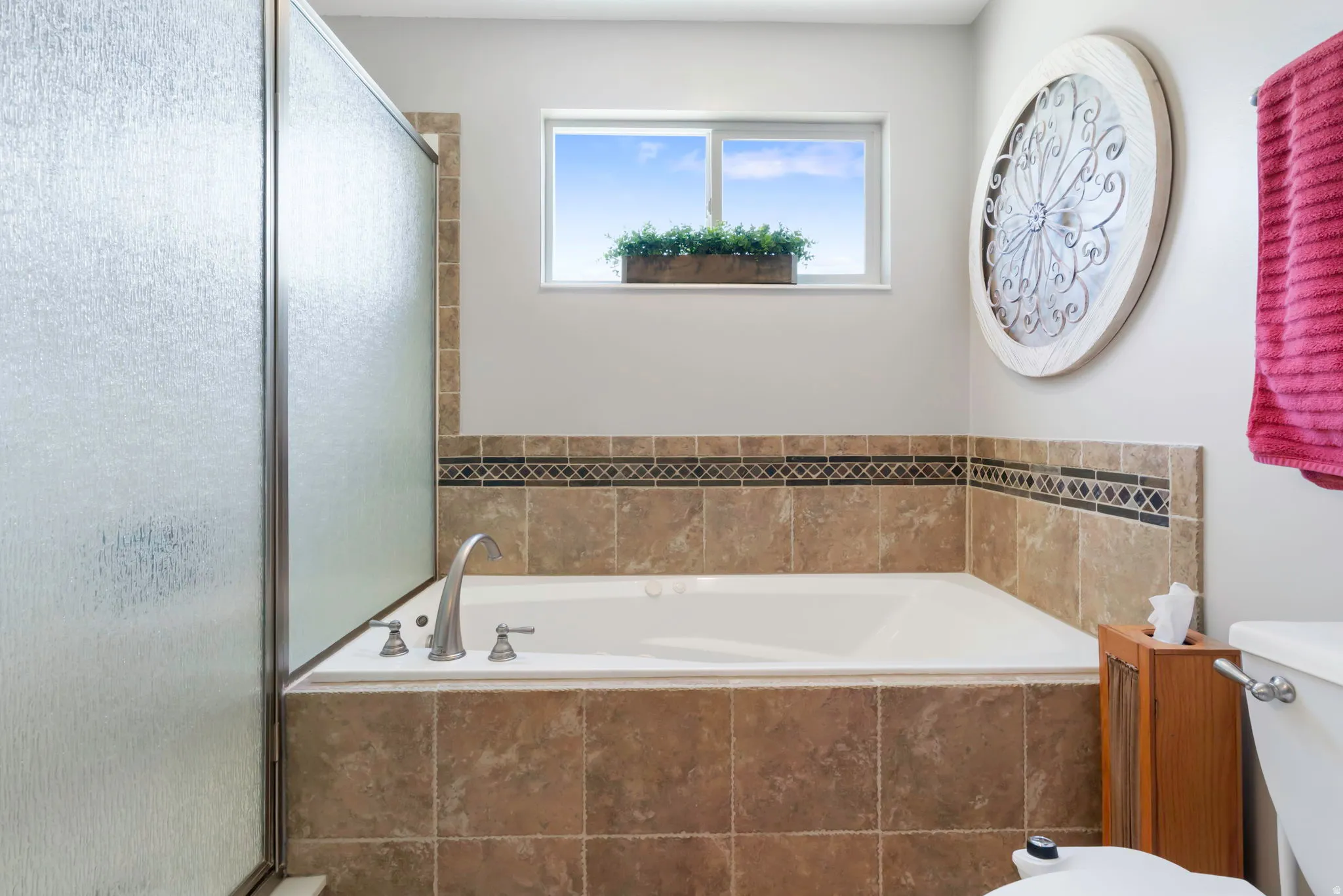 Soaking tub with tile surround and decorative mosaic accent band