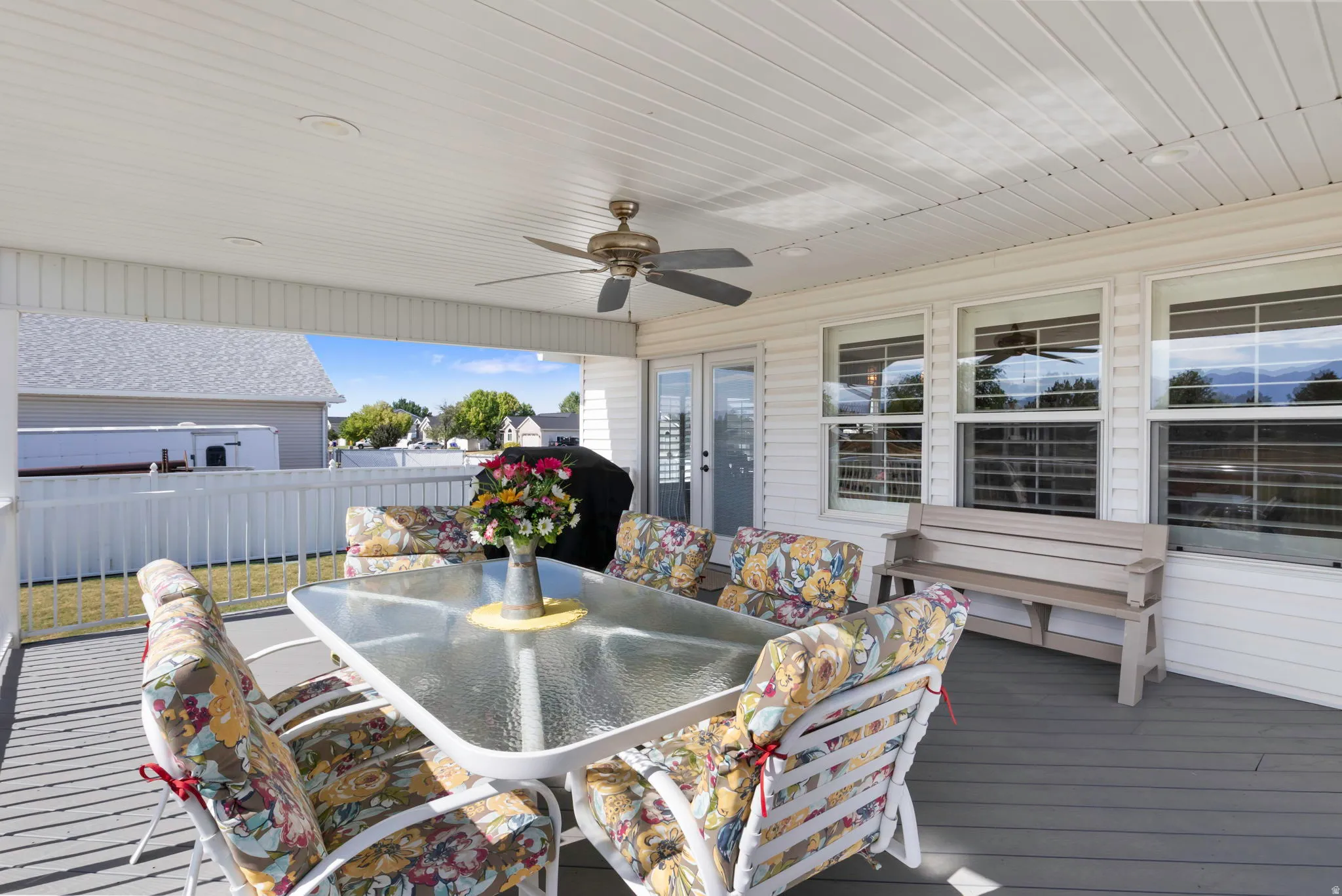 Covered outdoor deck with grey composite flooring and white vinyl siding