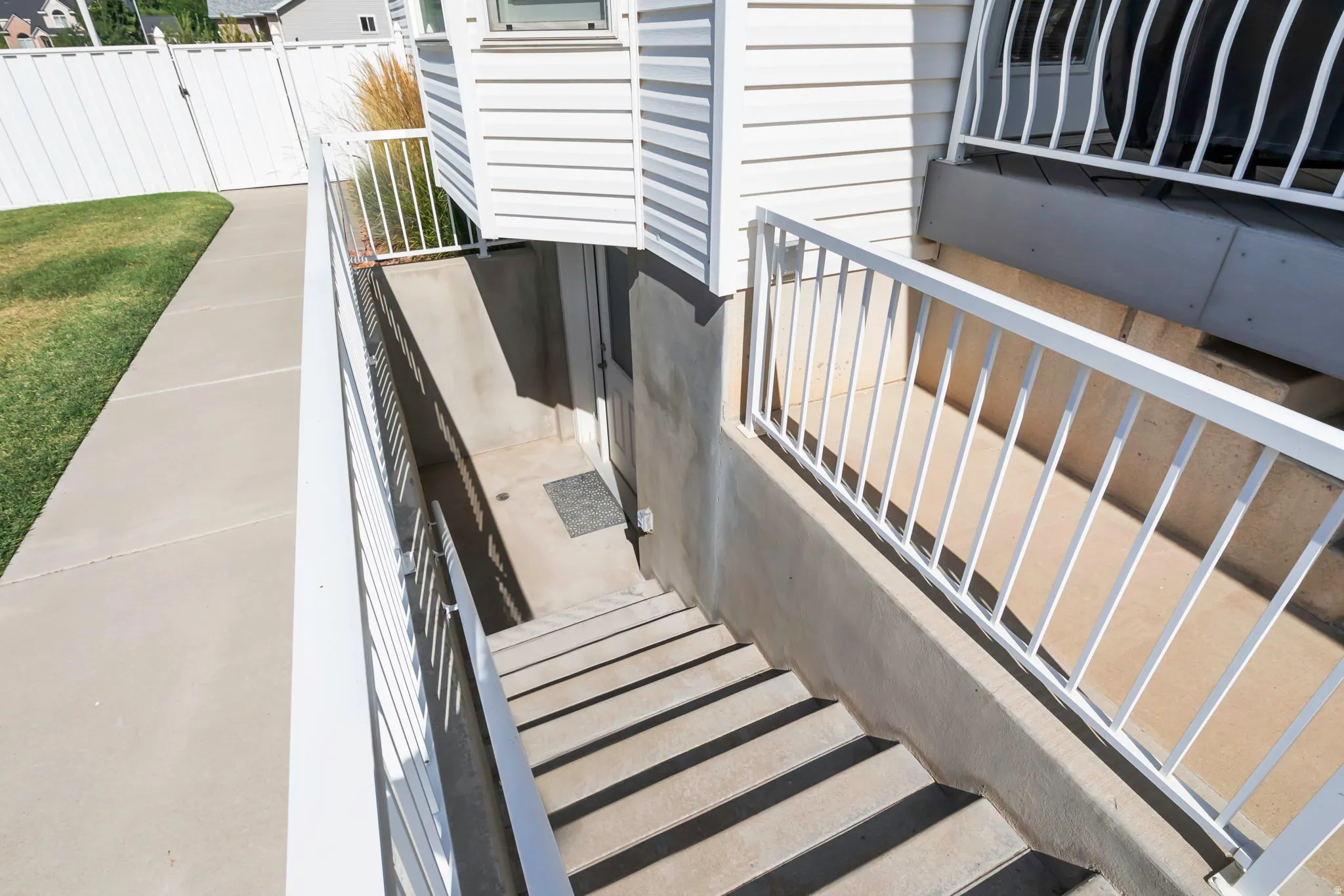 Exterior stairs leading to a lower-level entry, featuring white painted railings and concrete steps