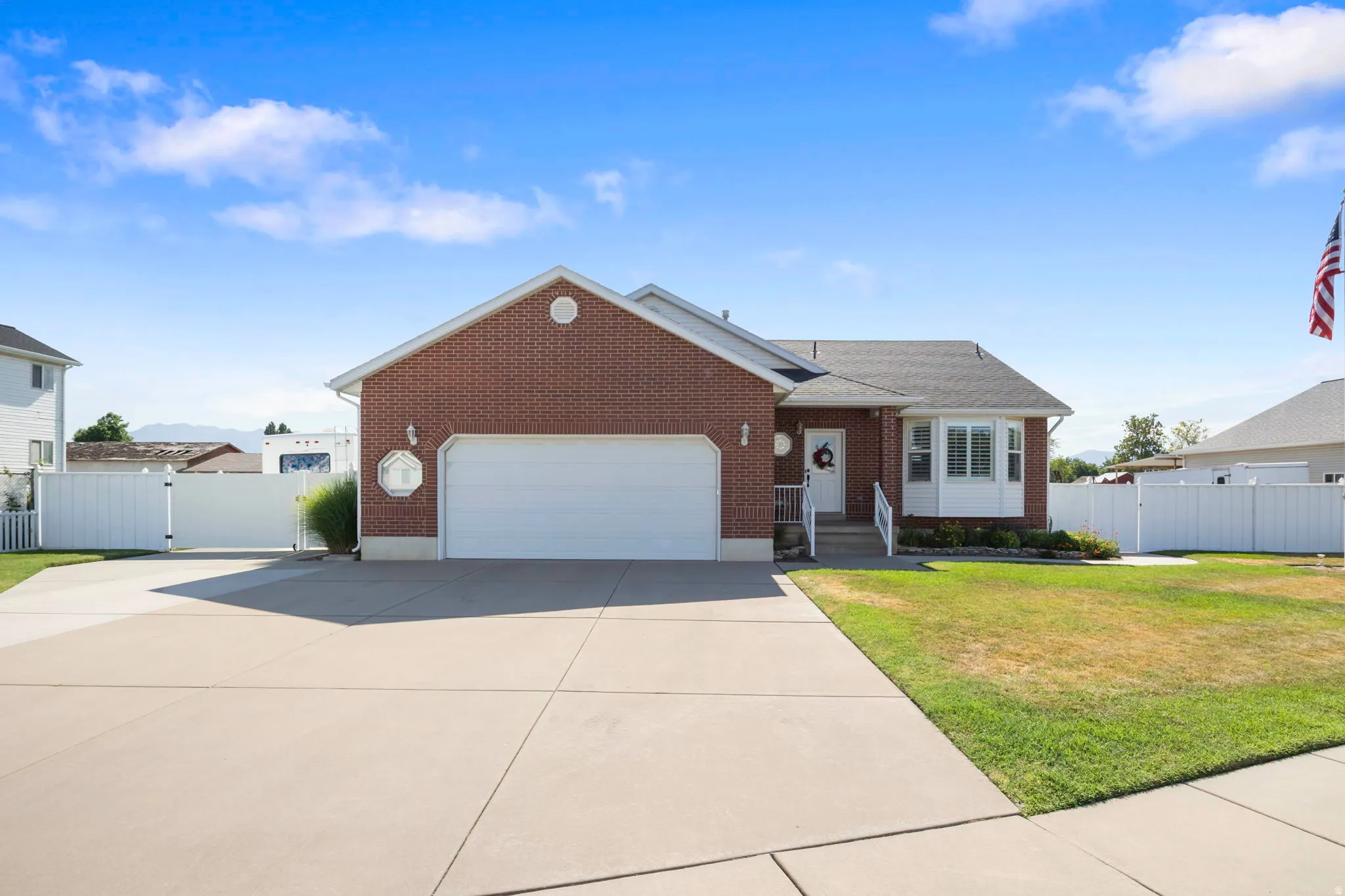 Brick exterior with a prominent two-car garage, concrete driveway, and front lawn