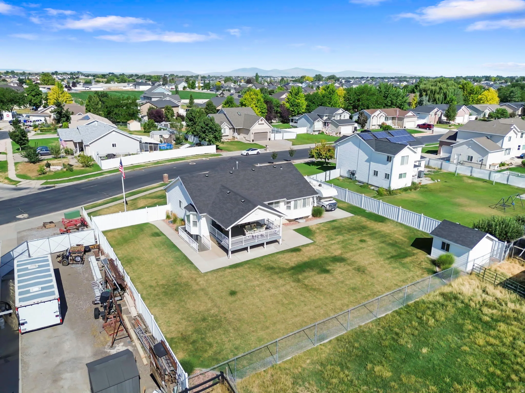 Expansive backyard featuring a large green space, white privacy fencing, and a dedicated storage shed