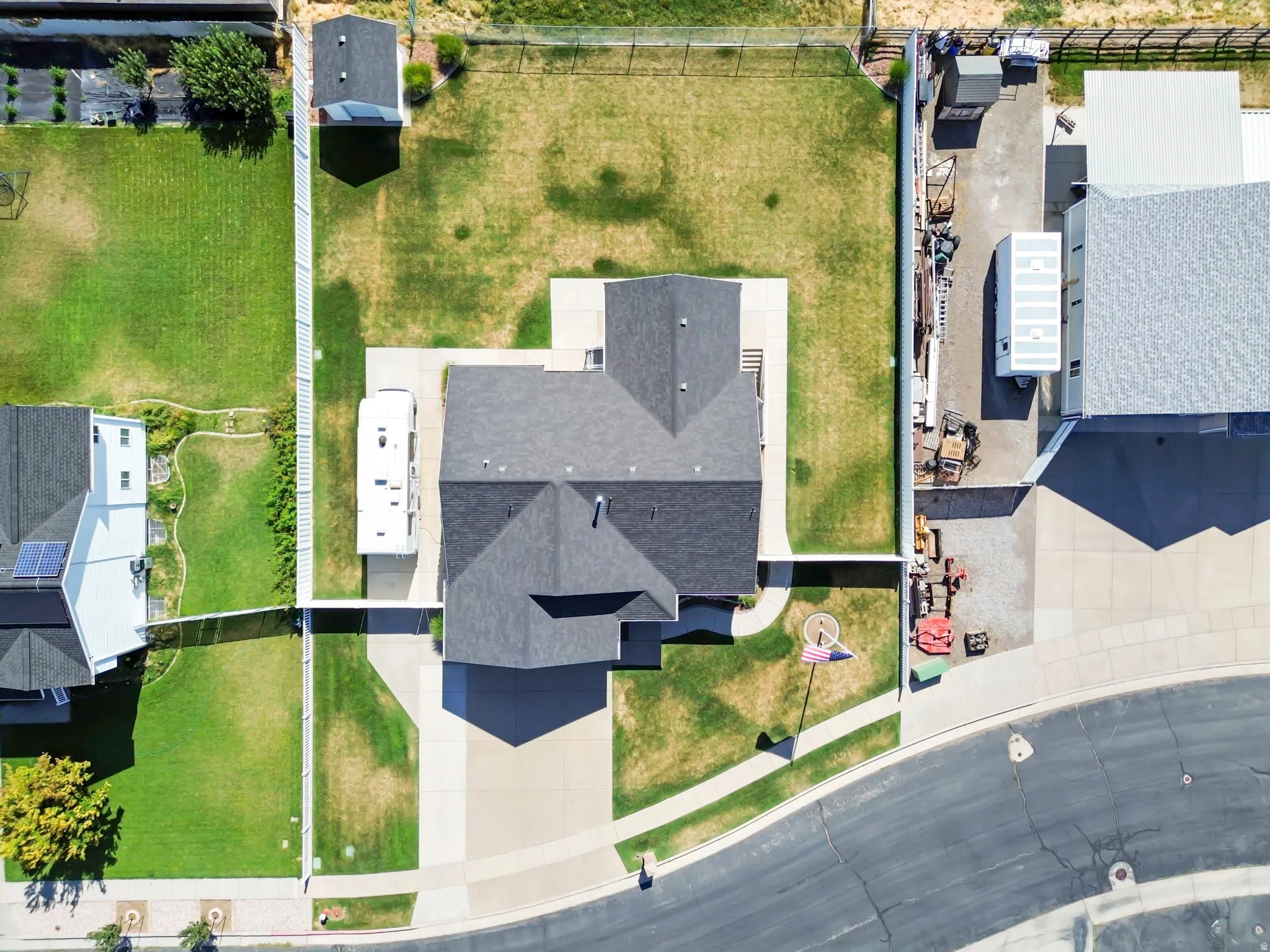 Overhead view of a property featuring a dark-shingled roof and a concrete driveway