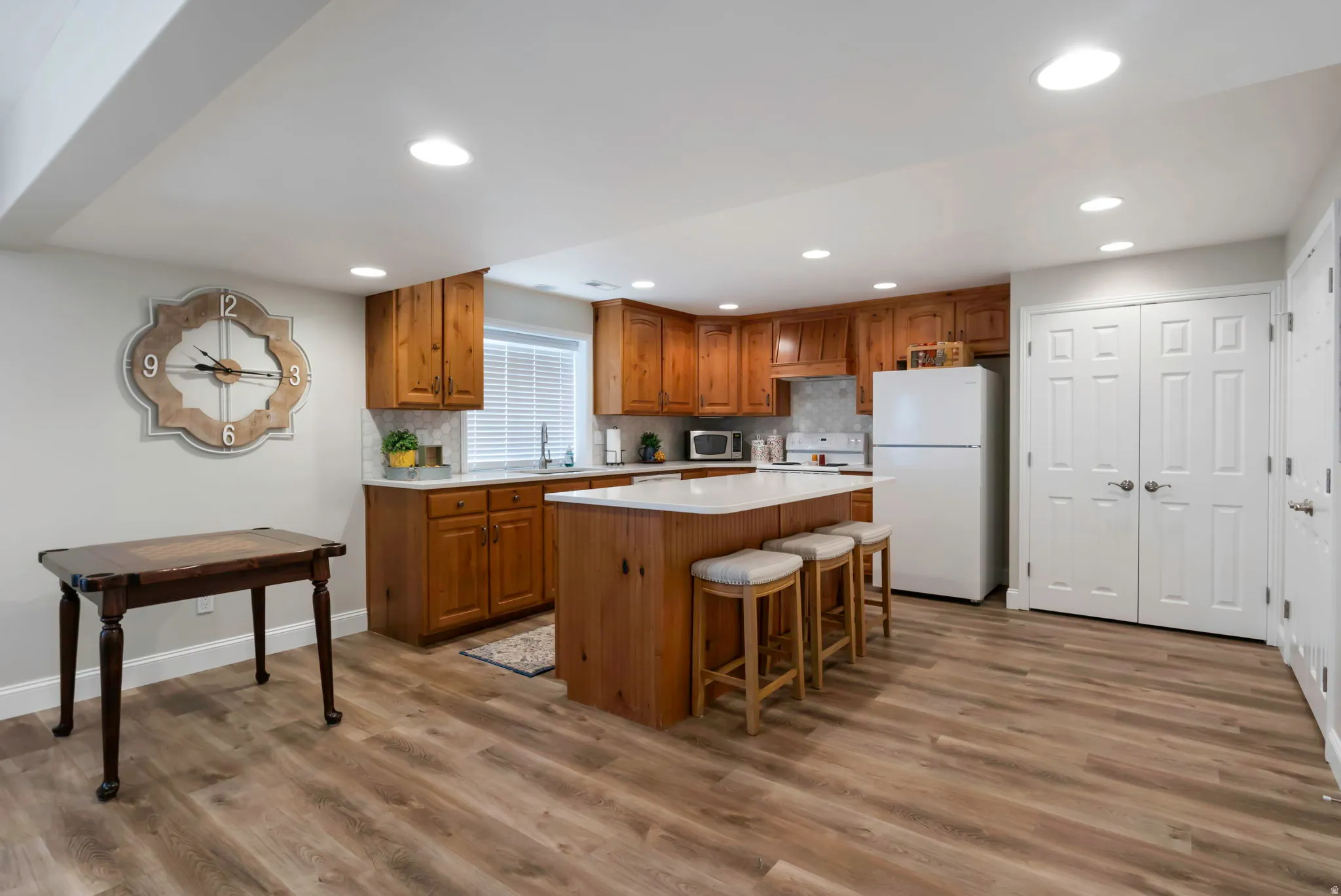 Full kitchen featuring wood cabinetry, white countertops, stainless steel sink, and wood-finish flooring