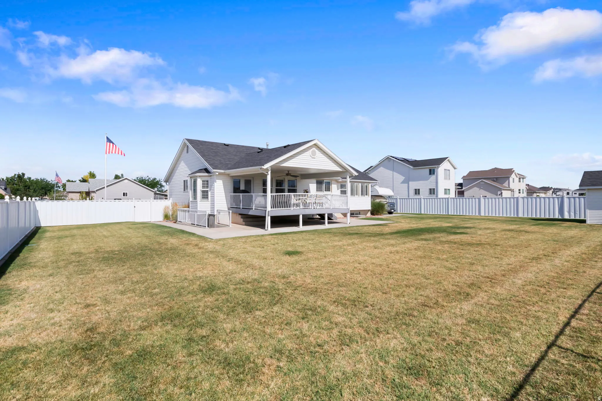 Expansive rear yard featuring a large manicured lawn and a full white privacy fence