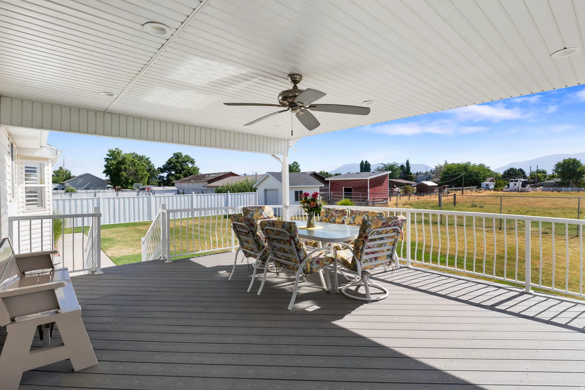 Expansive covered deck featuring composite decking, white railing, and a ceiling fan