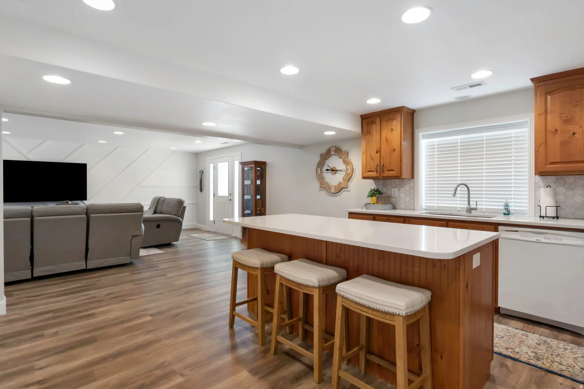 Open-concept living space featuring wood-finish flooring, recessed lighting, and a kitchen island with a light-toned countertop