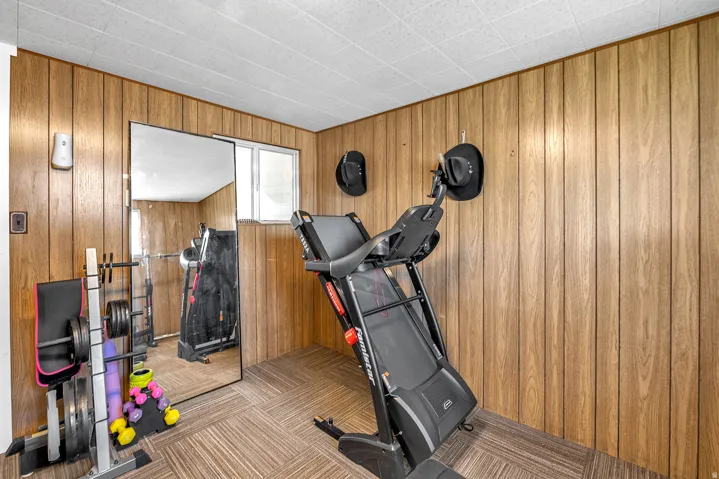 Room featuring wood-finish paneling, a drop ceiling, and patterned carpet flooring