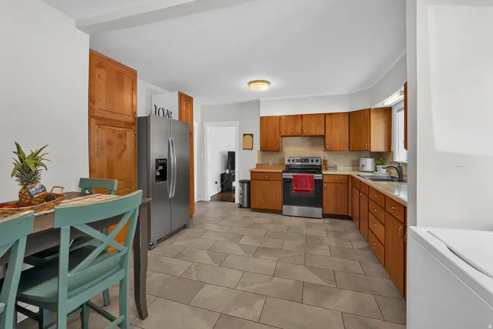 Kitchen featuring wood cabinetry, stainless steel appliances, light-toned countertops, and tile flooring