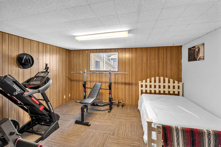 Versatile room featuring wood paneling, a drop ceiling with fluorescent lighting, and a window
