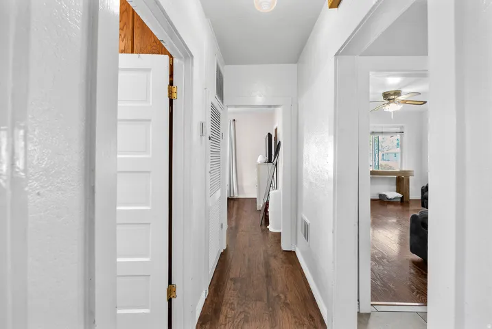 Hallway featuring wood-finish flooring, white painted walls, and multiple panel doors