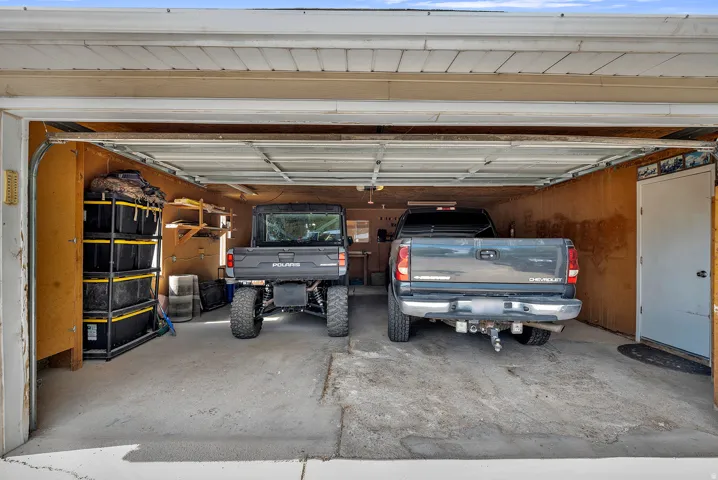 Spacious two-car garage featuring a concrete floor, plywood-paneled walls, and built-in shelving