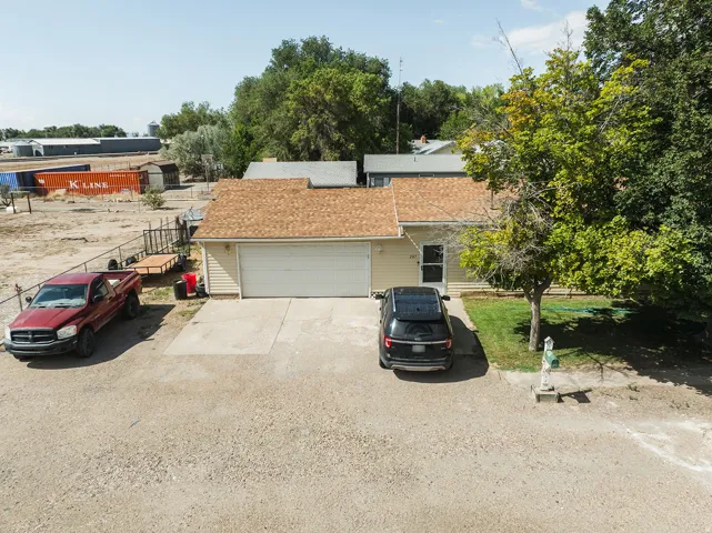 Single-story residence featuring siding exterior, an attached garage, a paved driveway, a shingle roof, and a front lawn with mature trees