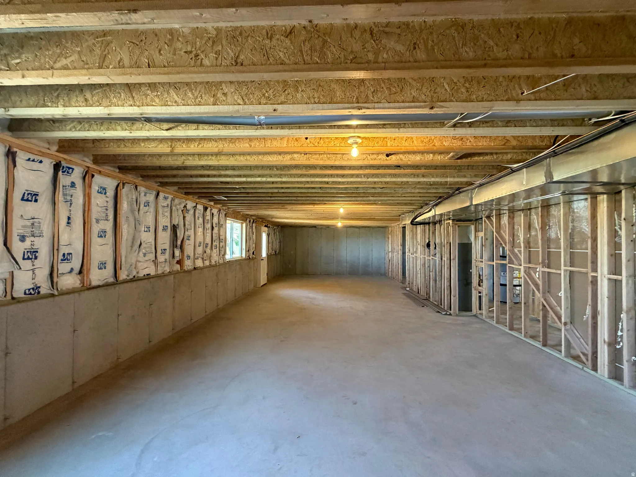 Expansive unfinished lower level featuring exposed wood joists and concrete flooring