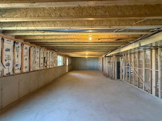 Expansive unfinished lower level featuring exposed wood joists and concrete flooring