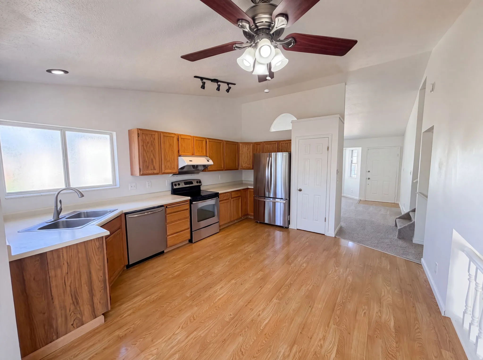 Kitchen featuring wood-finish flooring, wood cabinetry, white countertops, and stainless steel appliances