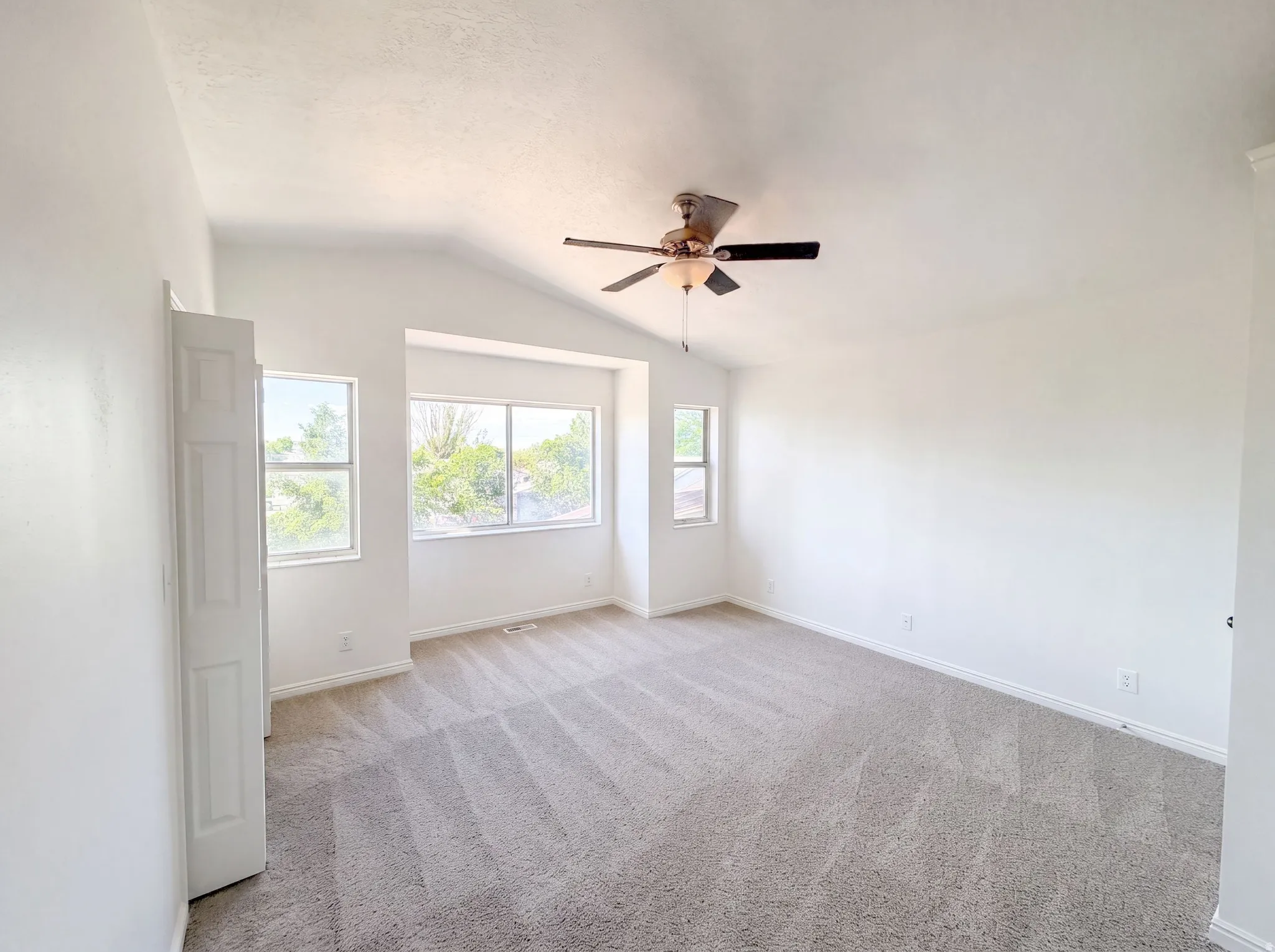 Spacious room featuring vaulted ceilings and neutral-toned carpeting