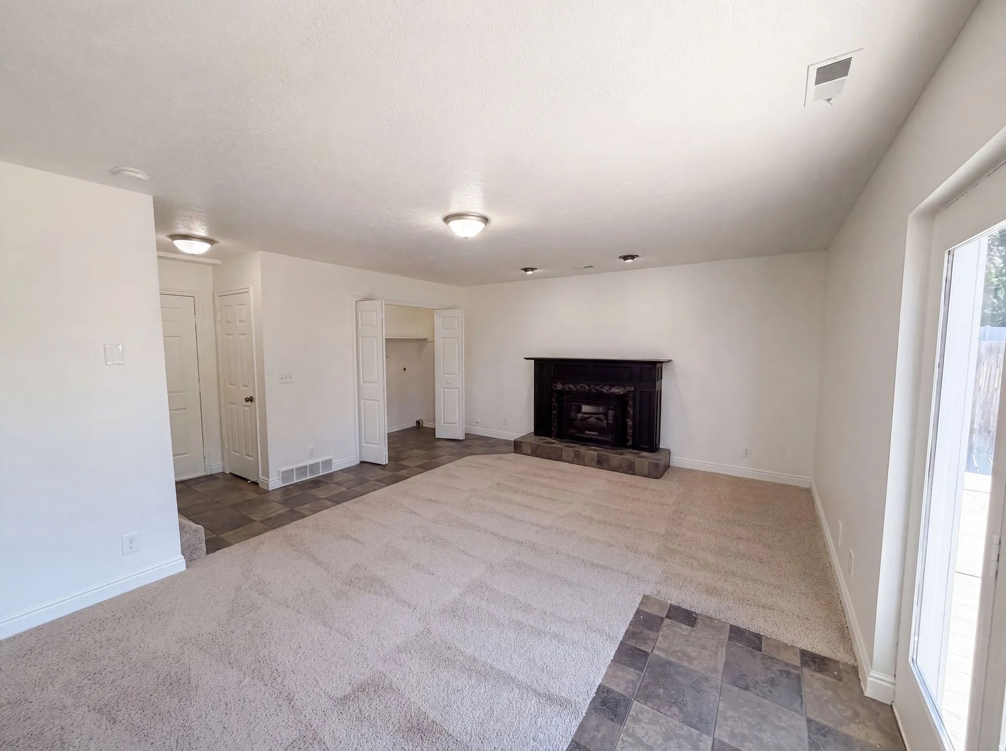 Spacious interior with neutral carpeting and square tile flooring
