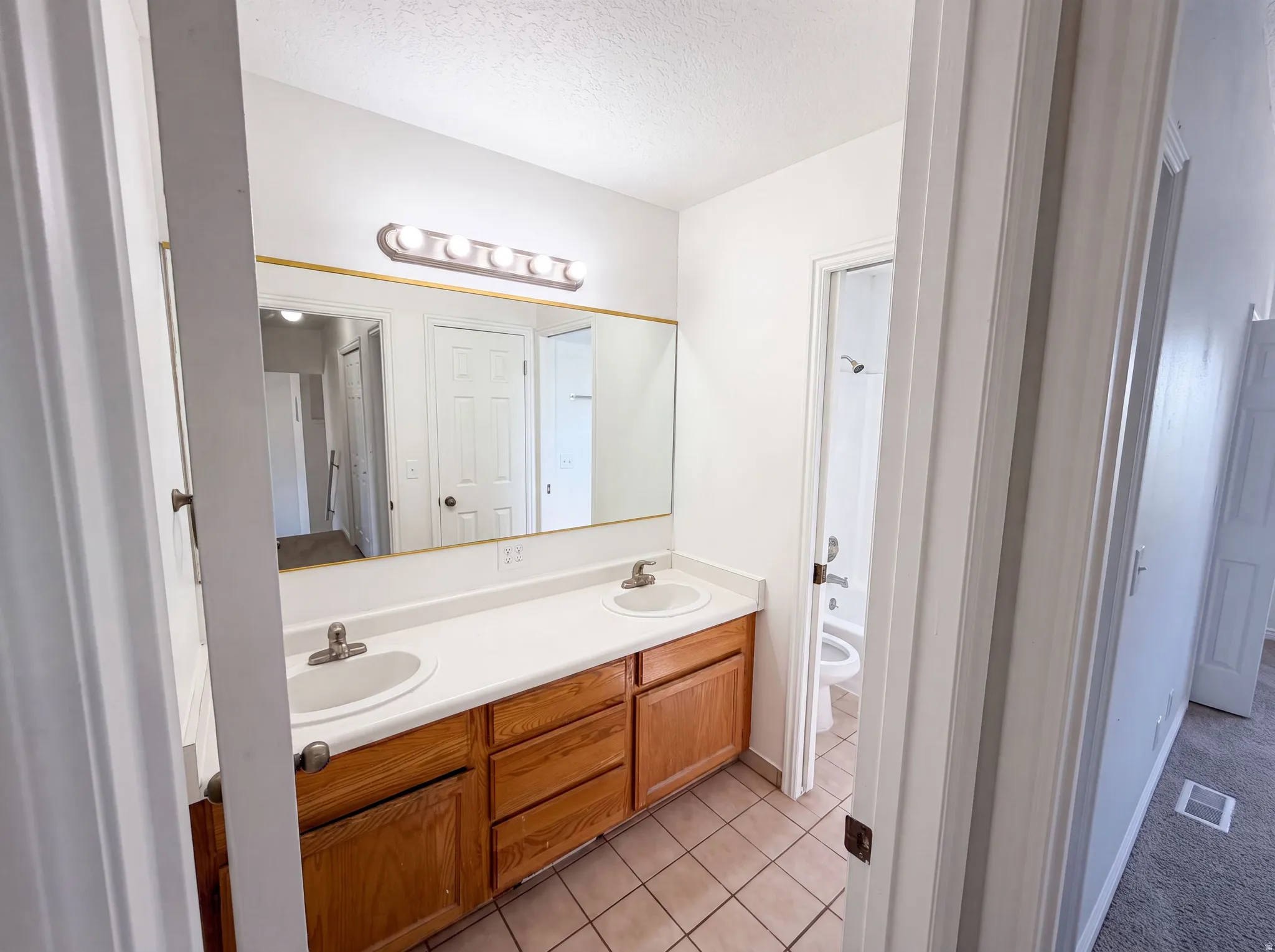 Bathroom featuring a dual vanity with light-tone wood cabinetry, white countertops, and integrated sinks