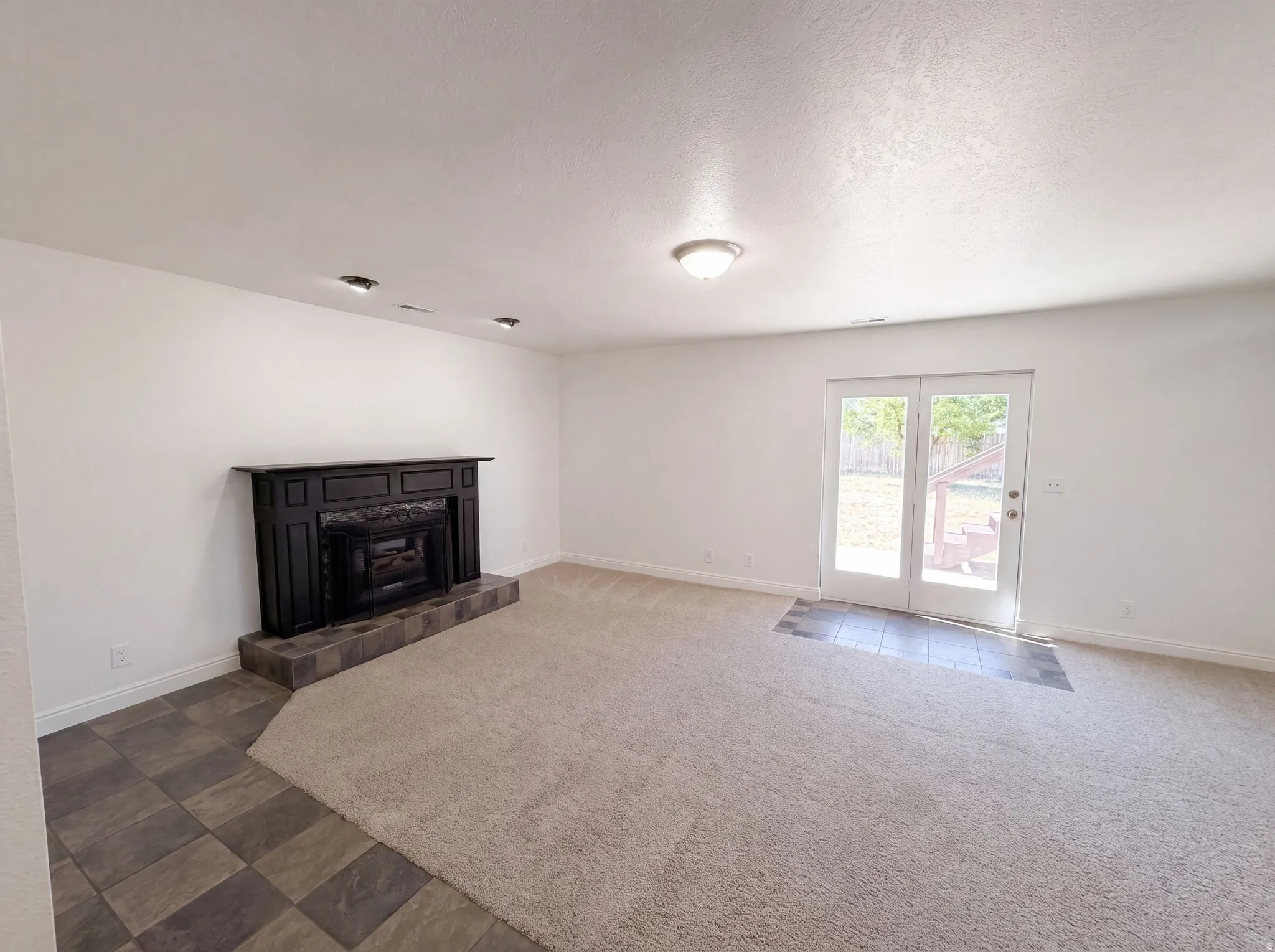 Living area featuring a black fireplace mantel, a tiled hearth, and light-colored carpeting