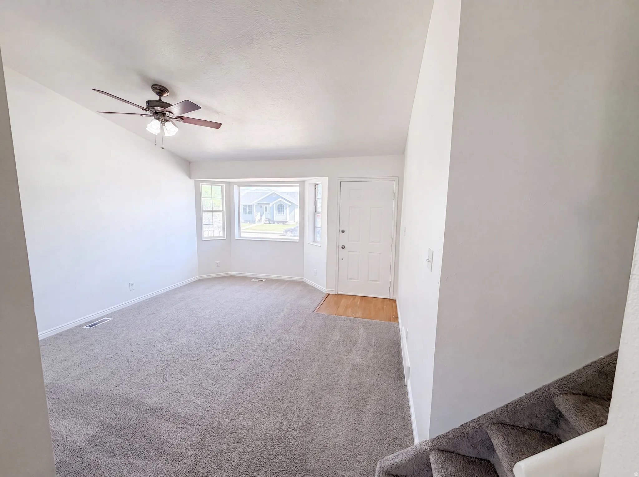 Entry area featuring a white paneled door, wood-finish flooring, and light gray carpeting