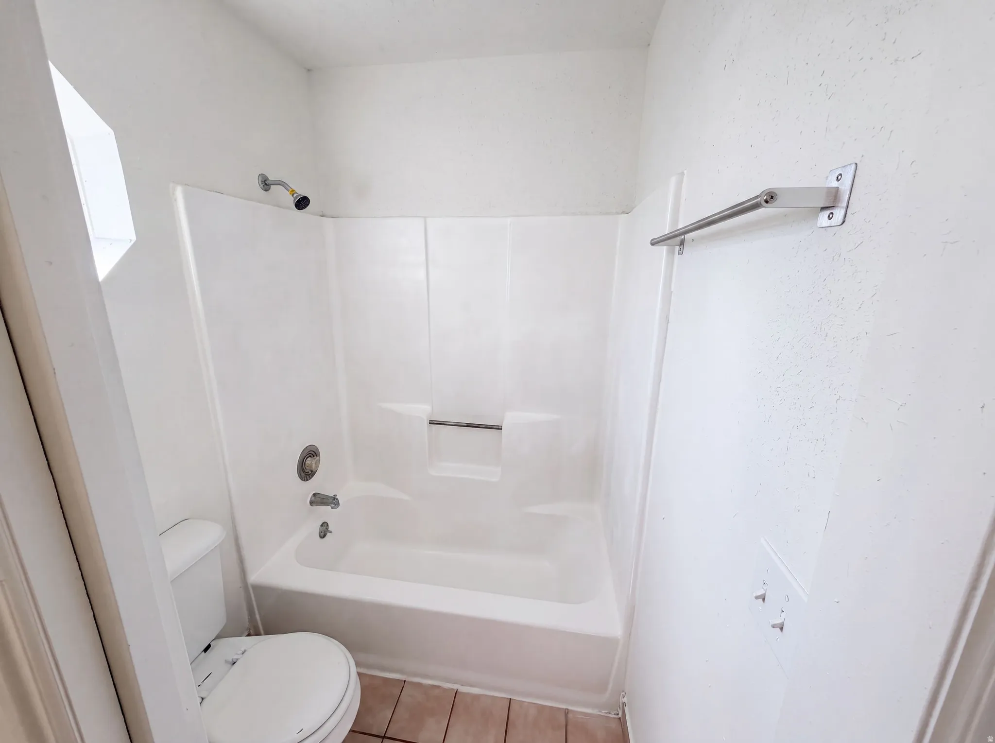 Full bathroom featuring a white tub/shower combination, white toilet, and tile flooring