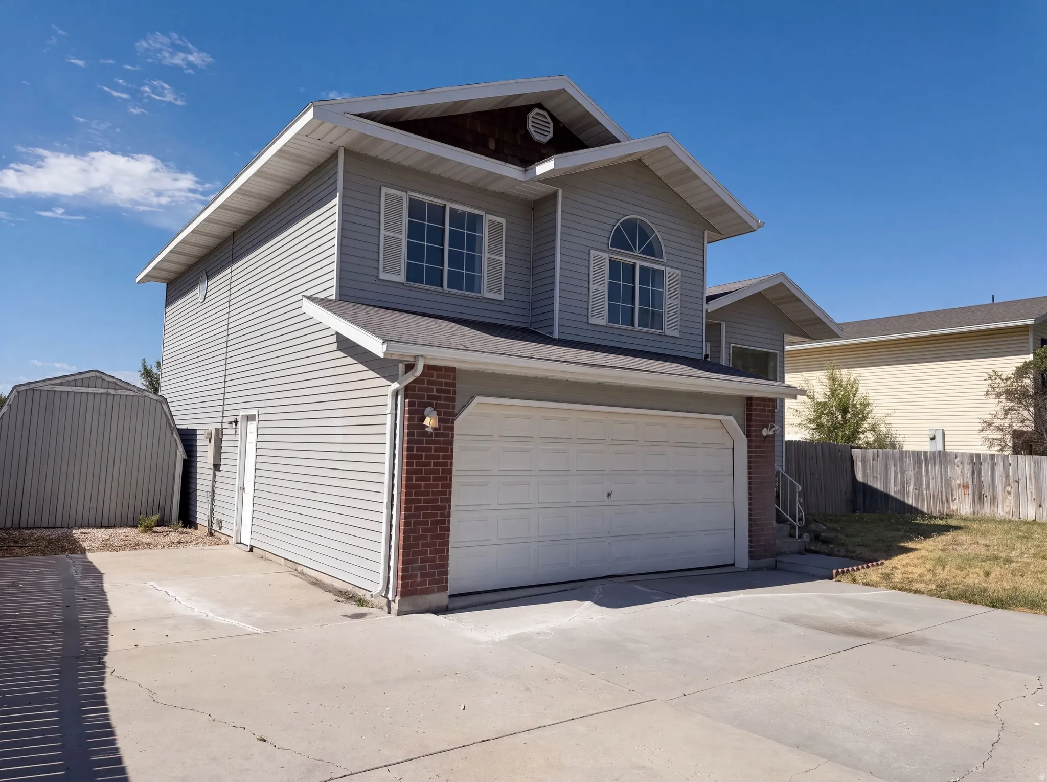 Two-story residence featuring light gray siding, a two-car garage, and a concrete driveway