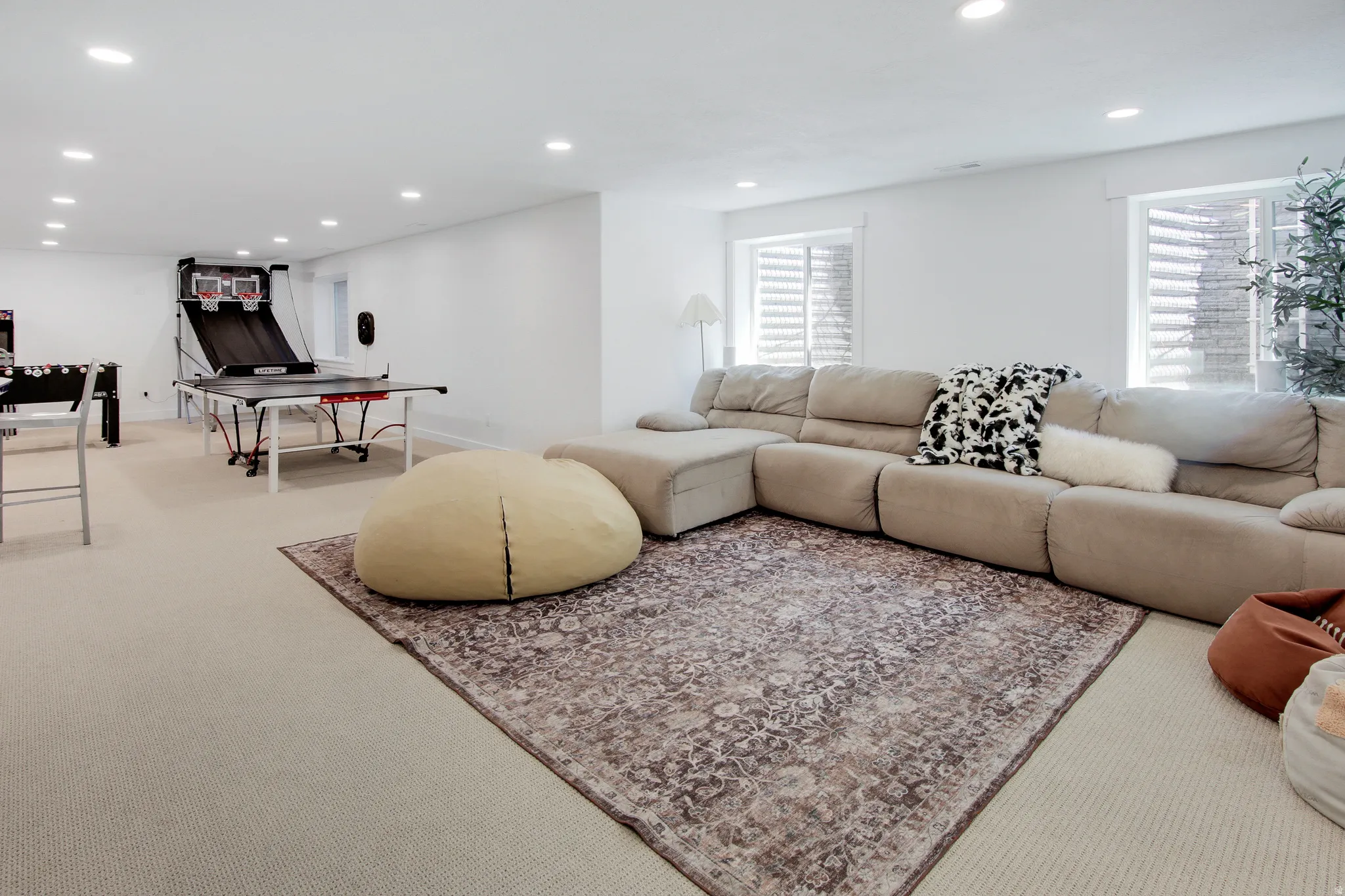 Spacious lower-level entertainment area featuring recessed lighting, light-toned carpeting, and a large area rug