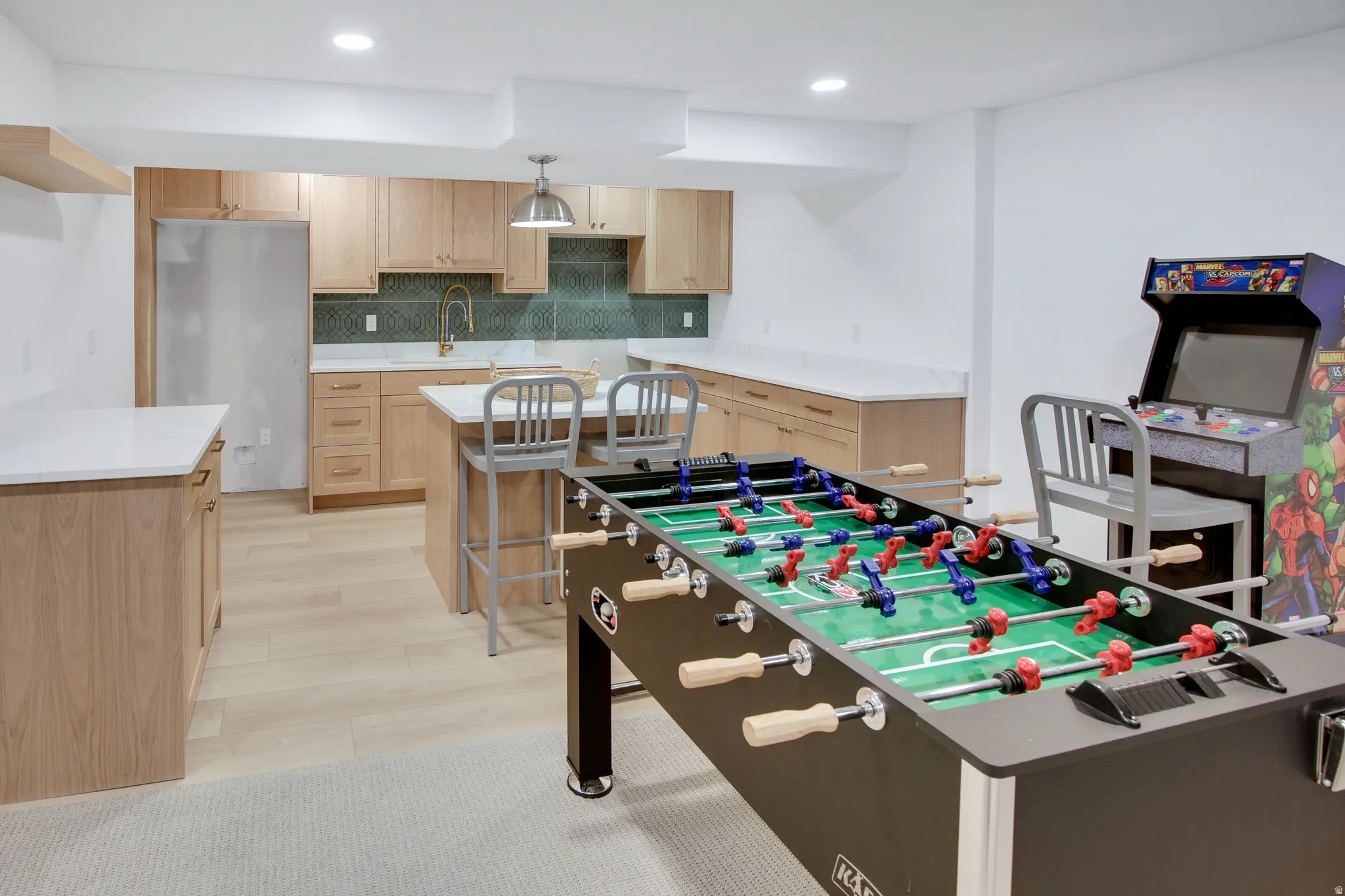 Well-appointed entertainment space featuring a functional wet bar with light wood-finish cabinetry, white countertops, and a patterned tile backsplash