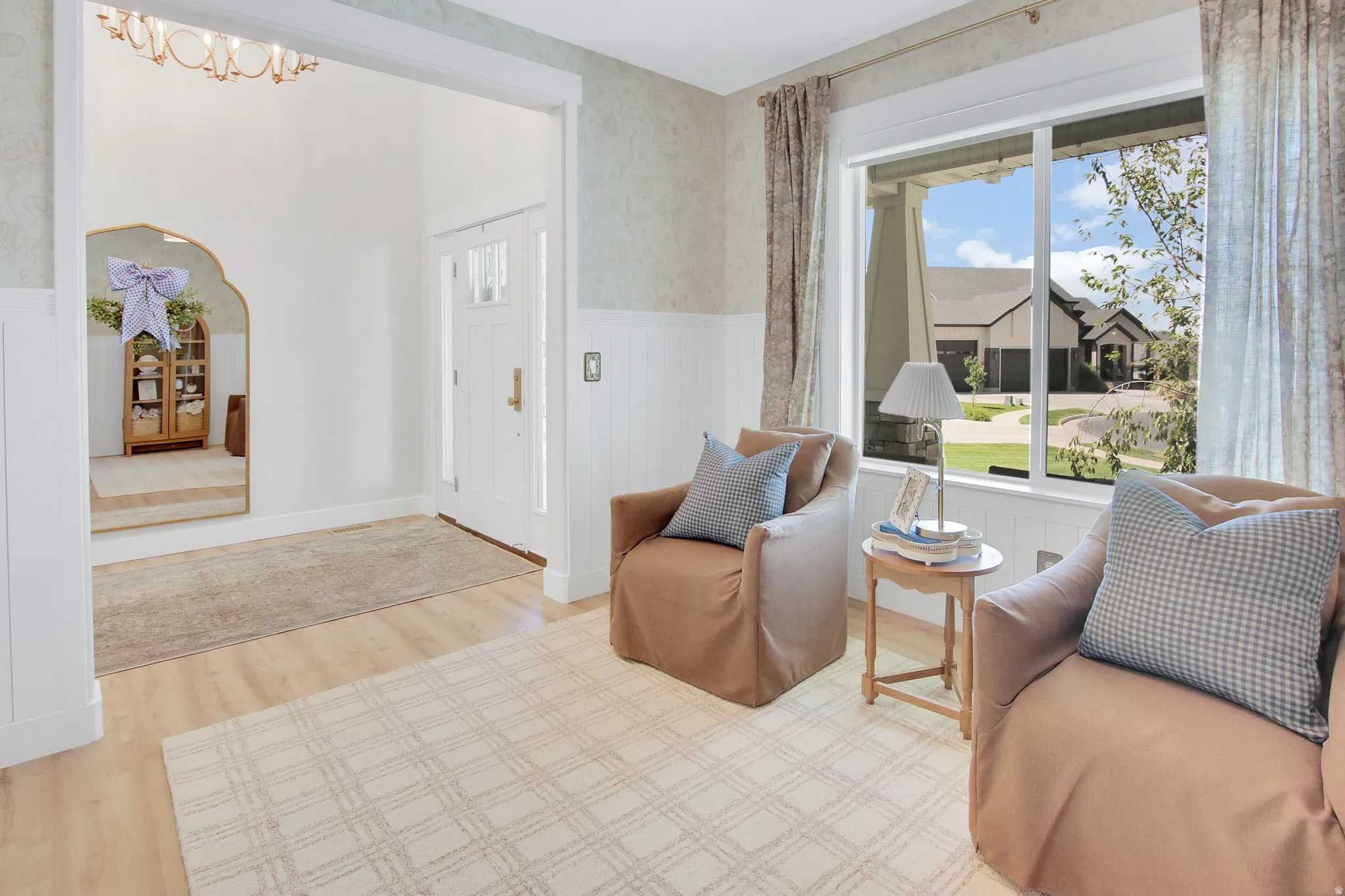 Spacious interior with light wood-finish flooring and a white paneled entryway